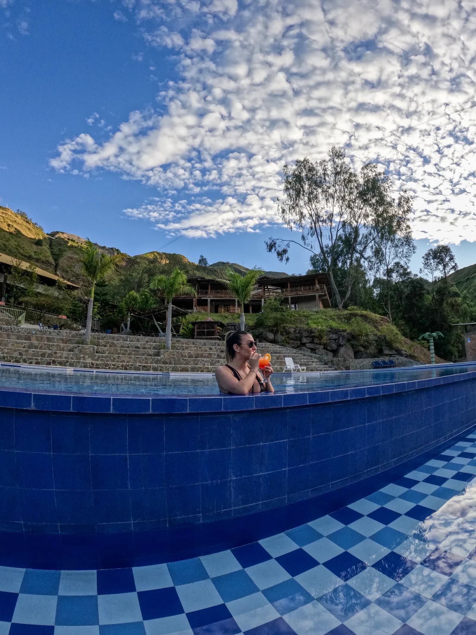 Persona disfrutando la piscina de Mawá con las cabañas de fondo